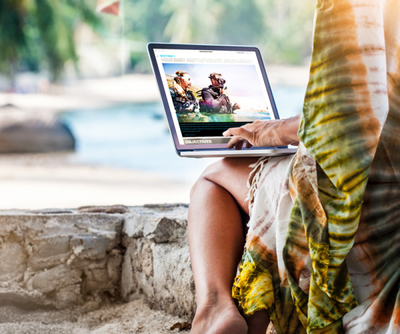 Woman sitting wtih her laptop on the Beach, checking out SSIs digital platform MySSI