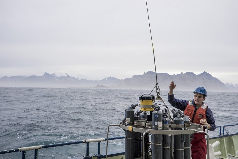Nick Foukal of the Woods Hole Oceanographic Institution helps deploy a set of instruments that perform physical measurements in the water off the Greenland coast. © Carolina Nobre, Woods Hole Oceanographic Institution
