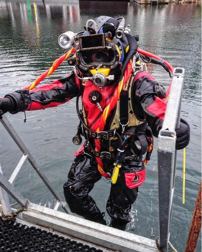 Professional diver Christopher Hokkanen climbing from the water in commercial diving equipment