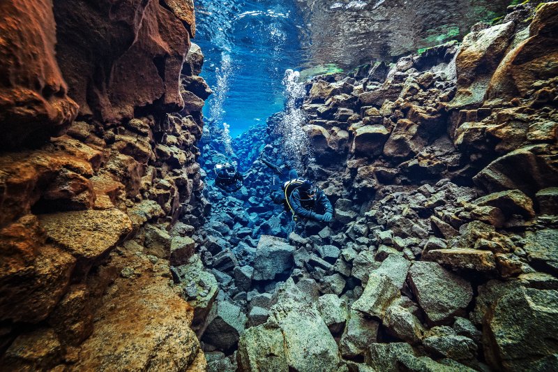 Dry suit diver moving through the clear blue water of Silfra in Iceland